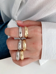 Macro shot of geometric faceted metal rings in gold and silver finish stacked on hand
