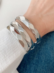 Detail shot of silver geometric faceted metal bracelets with polished finish and hinge design