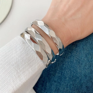 Set of three silver wave textured bangles with geometric faceted finish on model