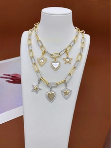 Detail of layered gold and silver mixed-metal chain necklace with crystal star and heart charms