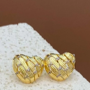 Gros plan de boucles d'oreilles cœur dorées avec texture tressée et zircons