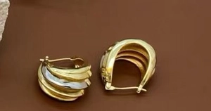 Detail of layered brass earrings with gold and silver two-tone curved leaf design