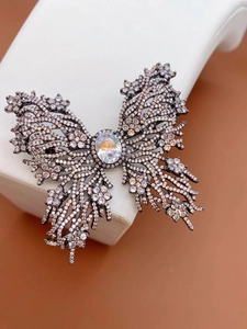 Close-up of butterfly brooch featuring dark metal wings and crystal oval centerpiece