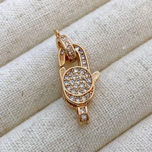Macro view of rose gold lobster clasp with micro-pave cubic zirconia on textured fabric