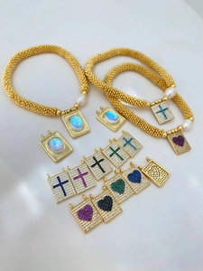 Detail showing gold bead necklaces with pearl accents and colorful zircon cross heart charms