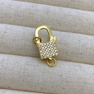 Détail macro du fermoir mousqueton doré orné de zircons cubiques micro-pavés