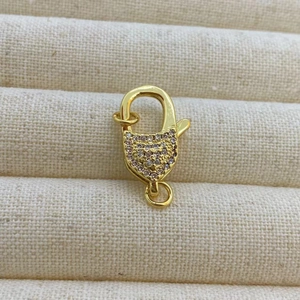 Détail macro du fermoir mousqueton doré avec sertissage de zircons roses scintillants