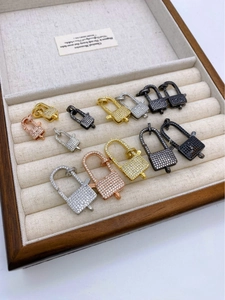 Macro detail of 18K gold and silver padlock pendants with pavé zircon settings for DIY jewelry