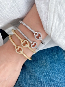 Nahaufnahme von herzförmigen Pavé-Armbändern in Gold und Silber an einem Modell