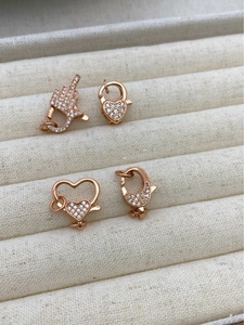 Macro detail of 18K rose gold lobster clasps and heart charms set with cubic zirconia