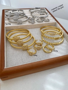 Close-up of 18K gold plated square zircon bracelets and rings on a jewelry tray