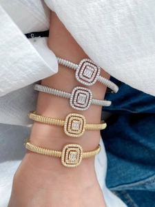 Detail of square zircon bangle in gold and silver finish with ribbed metal texture