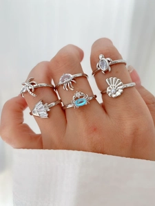 Macro detail of ocean theme ring set featuring sea turtle, crab and shells with blue stones