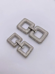 Detailed view of silver interlocking geometric clasps paved with sparkling zircons