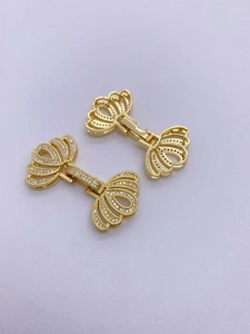 Vista macro di una chiusura a fiocco in oro 18K con zirconi lucenti e connettore per perle