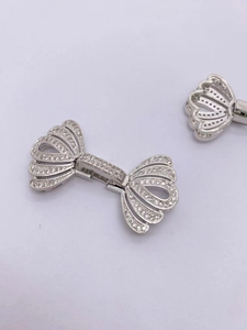 Dettaglio di accessori a forma di fiocco argento con zirconi scintillanti e base in metallo
