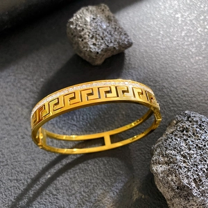 Gold double-layered greek key bangle with inlaid cubic zirconia on dark volcanic stones