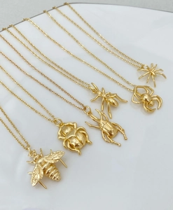 Vue macro détaillée de six pendentifs insectes dorés avec abeilles et araignées sur chaînes