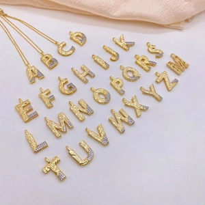 Detailed macro view of 26 gold letter pendants with hammered texture and cubic zirconia crystals
