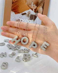 Vue détaillée des pendentifs alphabet argentés sertis de cristaux formant le mot HOPE