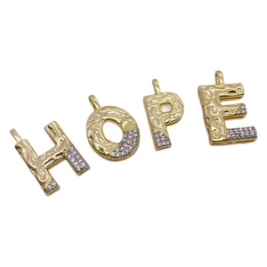 Detail of 18k gold plated letter pendants with hammered texture and zircon insets