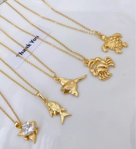 Detailansicht goldener Meeres-Halsketten mit Motiven wie Schildkröte, Krabbe und Rochen