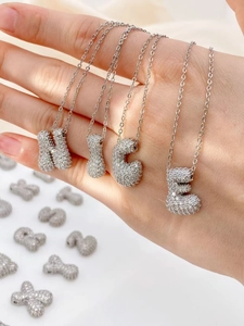 Macro-opname van zilveren letterhangers met glanzende zirkonia-kristallen bezet