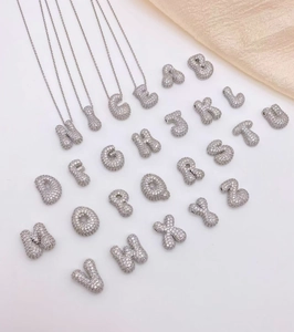 Macro-opname van zilveren bubble letter hangers bezet met fonkelende zirkonia steentjes