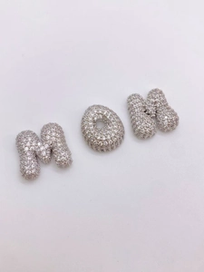 Macro-opname van zilveren MOM-letterhanger met witte zirkonia-stenen voor doe-het-zelf ketting