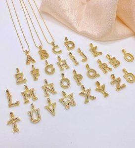 Macro shot of colorful zircon letter pendants and a cross with rainbow crystal inlay