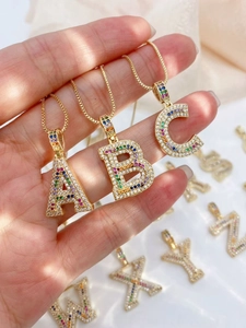 Detail of gold-plated alphabet pendants A, B, C with vibrant rainbow cubic zirconia