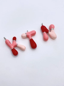 Detail of colorful bubble letters K, T, and N pendants with a glossy enamel finish