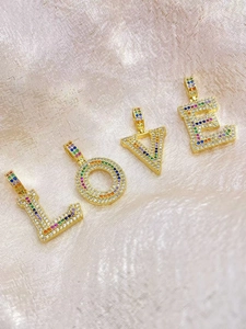 Detailed close-up of gold-plated LOVE letter pendants with rainbow cubic zirconia inlay