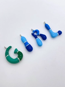 Detailed view of colorful bubble letter G-I-R-L pendants with vibrant enamel finish
