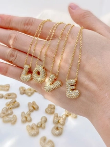 Dettaglio della collana con ciondolo LOVE dorato e zirconi a pavé tenuta nella mano