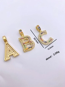Detailed view of gold square letter pendants with clear and colored cubic zirconia inlay
