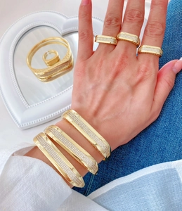 Détail de joncs et bagues géométriques plaqués or 18K avec sertissage micro-pavé