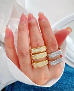 Détail de bagues carrées empilées serties de zircons en finitions or 18K et argent