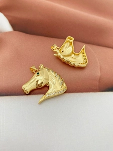 Close-up of 18K gold tiger pendant showing green stone eyes and zircon details