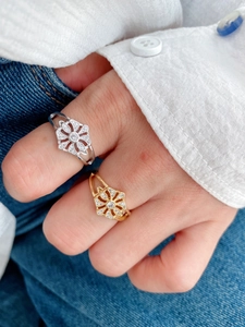Nahaufnahme eines Blumenrings mit Zirkonsteinen an einer Frauenhand im Alltag