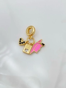Macro detail of gold-plated passport and graduation cap charms with black zircon heart