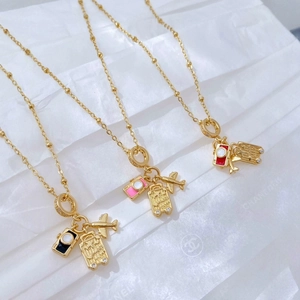 Detailed view of travel charms with camera, suitcase and airplane on golden bead chains