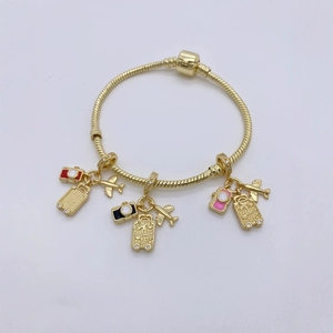 Detailed close-up of golden travel charms including a camera, suitcase, and plane on a chain