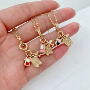 Detail of travel necklaces featuring camera, suitcase, and airplane gold pendants