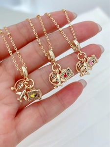 Detailed close-up of a gold travel-themed necklace with globe, plane and suitcase charms