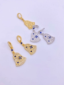 Detail view of bell pendants with white zircon pavé and blue stones in gold and silver