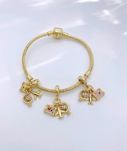 Detailed macro view of gold snake chain bracelet with airplane and globe travel charms