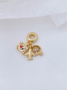 Macro detail of gold travel pendants featuring an airplane, globe, and heart luggage