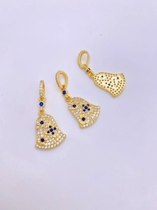 Macro detail of gold bell pendants with blue stones and honeycomb hollow back