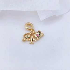 Gold travel charm necklace with globe, airplane and passport pendants on white fabric